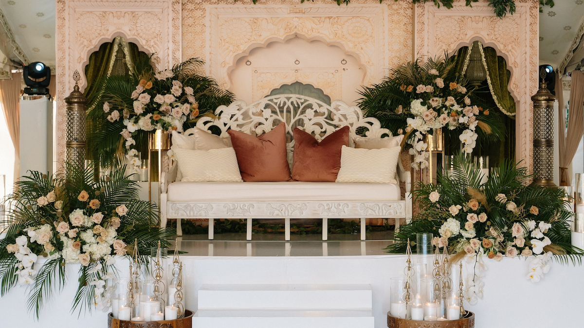 Intricately carved wooden Mandap with silk draping and floral arrangements for an Indian wedding.